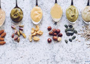 Nussmus auf Löffeln, darunter sind die Nusssorten aus denen das Nussmuß gemacht wurde