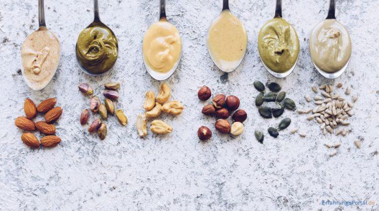 Nussmus auf Löffeln, darunter sind die Nusssorten aus denen das Nussmuß gemacht wurde