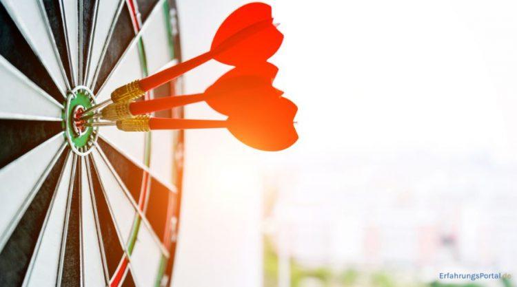 Drei Dartpfeile stecken in einer Dartscheibe