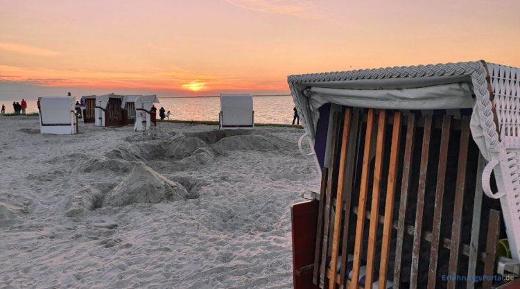 Strandkörbe am Strand. Im Hintergrund sieht man das Meer, den Sonnenuntergang und einige Personen