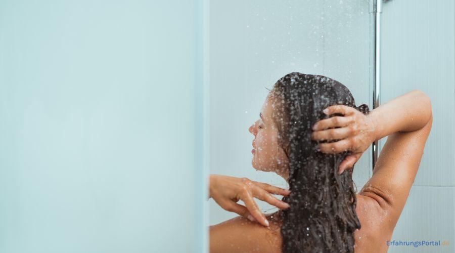 Frau wäscht ihre Haare unter der Dusche