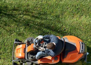 Mann sitzt auf einem Rasenmäher und mäht Rasen