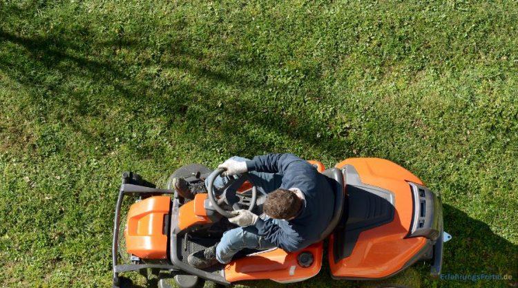Mann sitzt auf einem Rasenmäher und mäht Rasen