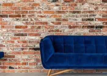 Blaues Sofa vor einer Steinwand