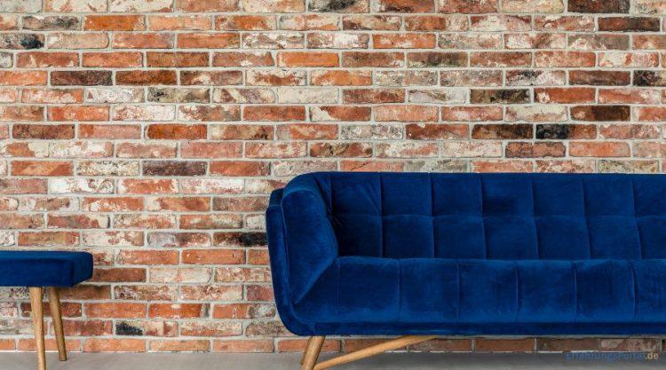 Blaues Sofa vor einer Steinwand