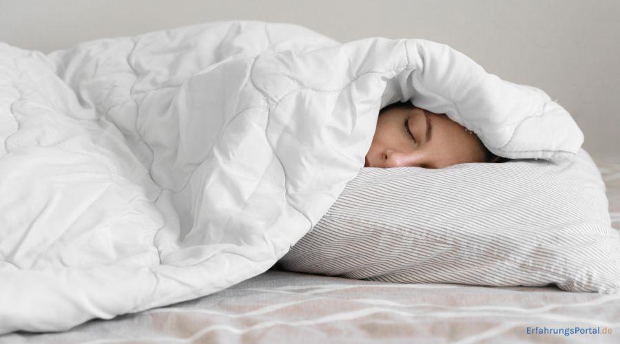 eine Frau schläft mit der Decke über dem Kopf