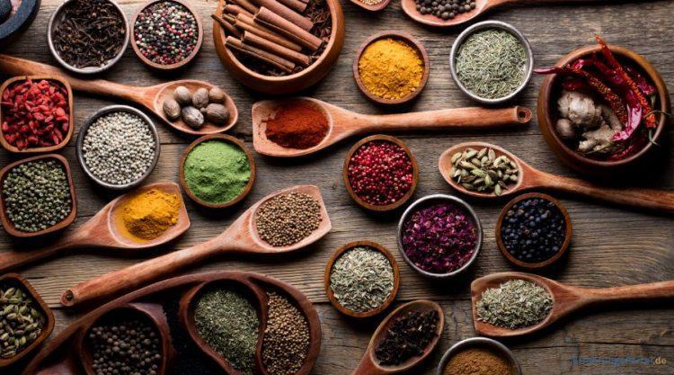 Gewürze auf Holzlöffel und in Holzschälchen