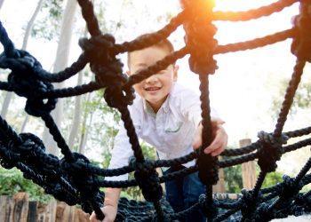 Junge klettert auf einem Spielgerät im Garten