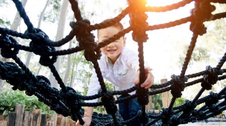 Junge klettert auf einem Spielgerät im Garten