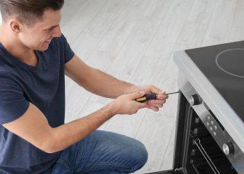 Ein Mann schraubt am Backofen