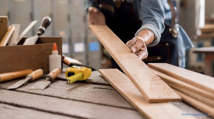 Schreiner begutachtet ein Stück Holz in seiner Werkstatt