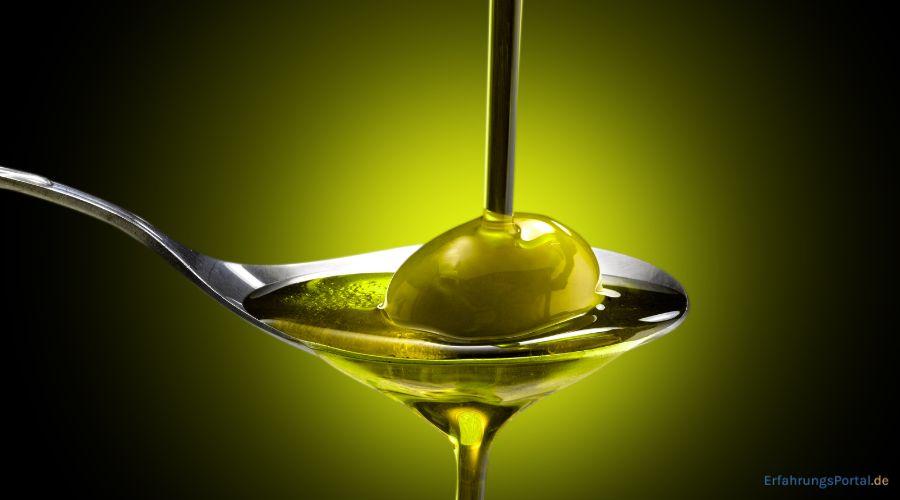 Olivenöl wird auf eine Olive gegossen