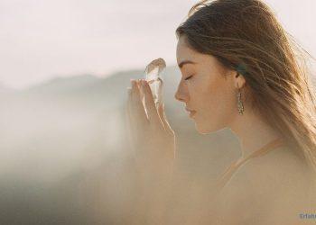 Frau hält ein Kristall in der Hand und hat die Augen geschlossen