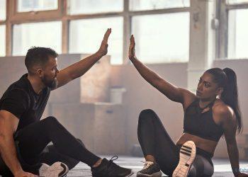 Mann und Frau sitzen nach dem Training auf dem Boden