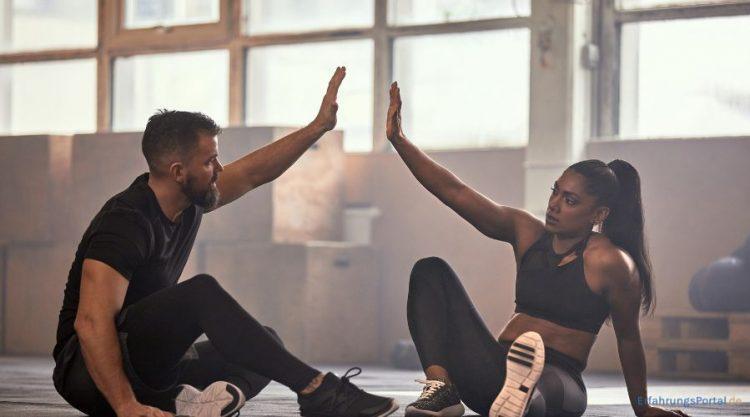 Mann und Frau sitzen nach dem Training auf dem Boden
