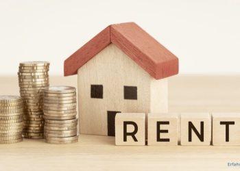 gestapeltes Kleingeld neben einem kleinen Holzhaus