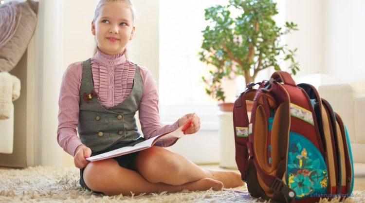 Schulkind mit Büchertasche und Schulheft