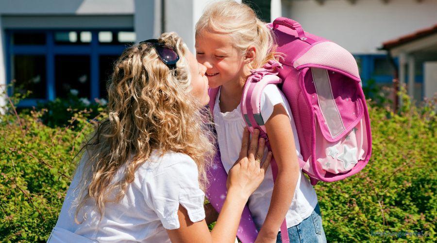 Mutter verabschiedet oder begrüßt Tochter vor der Schule