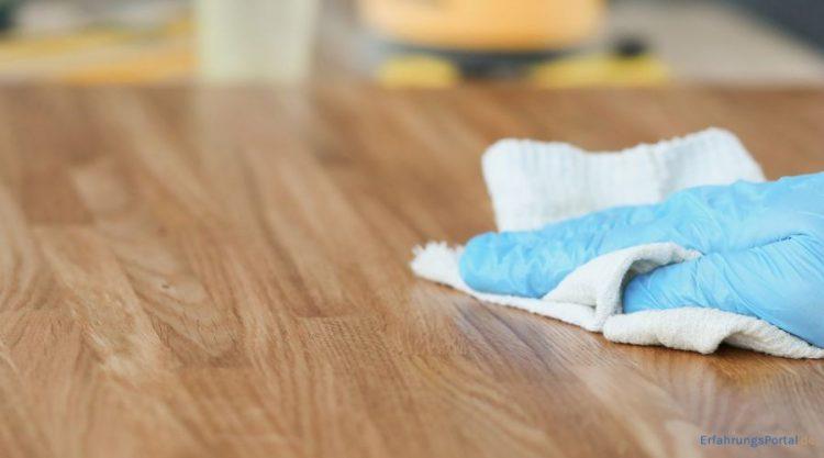 Eine Holzplatte wird mit einem Tuch sauber gewischt