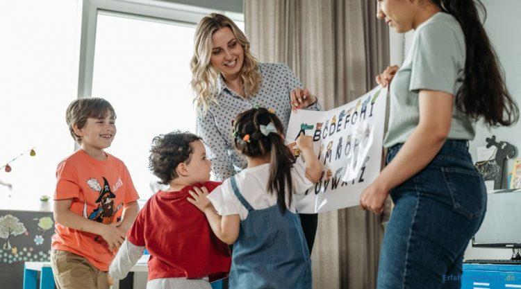 Erzieherinnen zeigen den Kindern ein Lernposter