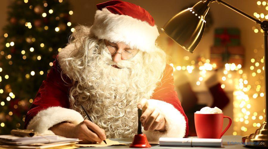 Der Weihnachtsmann schreibt einen Brief. Vor ihm steht eine schwarz-rote Glocke und eine heiße Schokolade in einer Roten Tasse. Im Hintergrund ist alles weihnachtlich geschmückt
