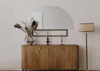 abgerundete Kommode mit Kerzen, einer Vase, einem Spiegel und einer Stehlampe