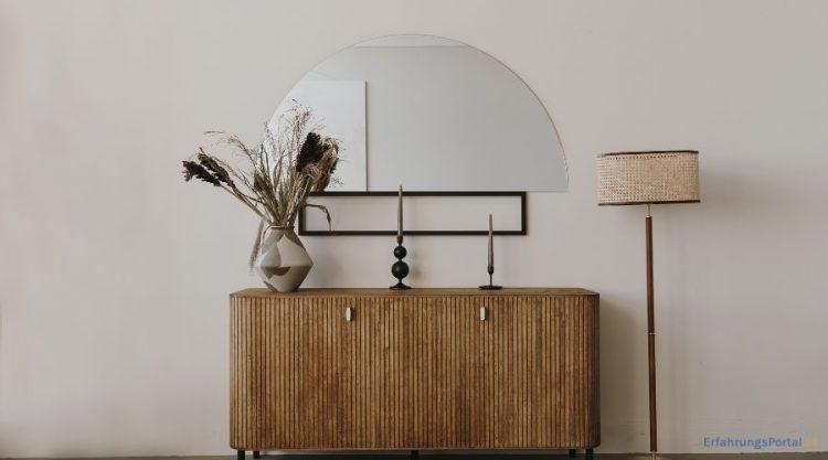 abgerundete Kommode mit Kerzen, einer Vase, einem Spiegel und einer Stehlampe