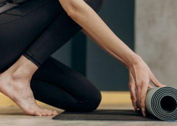 Frau rollt eine Yogamatte aus