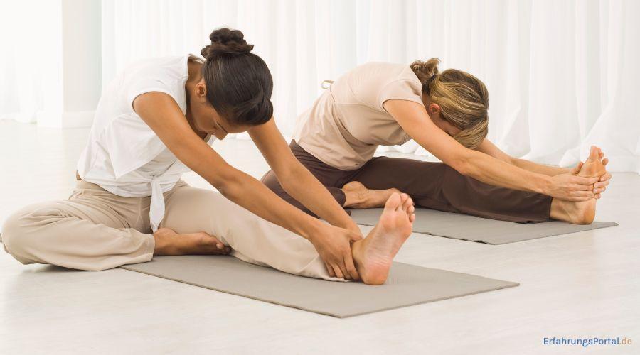 zwei Frauen sitzen auf ihren Yogamatten und dehnen sich