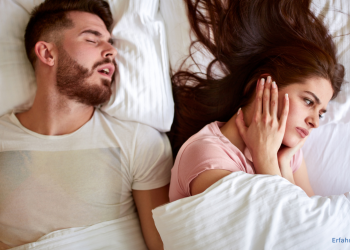 Frau hält sich die Ohren zu, weil der Mann neben ihr schnarcht