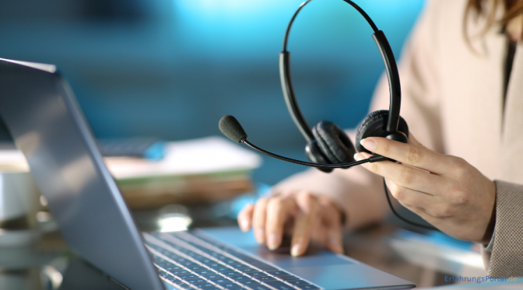 Jemand hält ein Headset in der Hand, während derjenige mit der anderen Hand etwas auf dem Laptop klickt