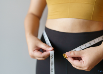 eine Frau misst ihren Bauchumfang