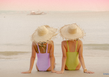 zwei Frauen in Badeanzug sitzen am Strand bei Sonnenuntergang
