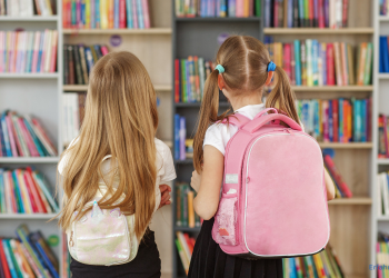 Zwei Mädchen mit einem Kinderrucksack auf dem Rücken