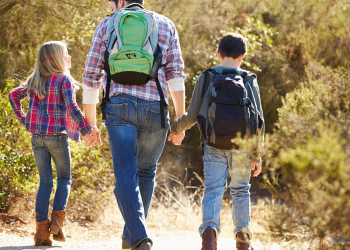 Ein Vater mit Kindern macht einen Ausflug und trägt einen Rucksack