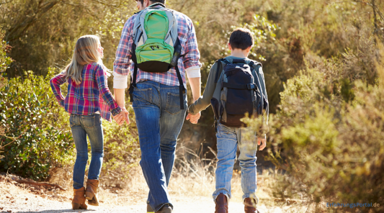 Ein Vater mit Kindern macht einen Ausflug und trägt einen Rucksack