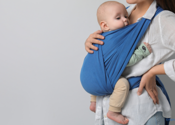 Frau trägt Baby in einer Babytrage